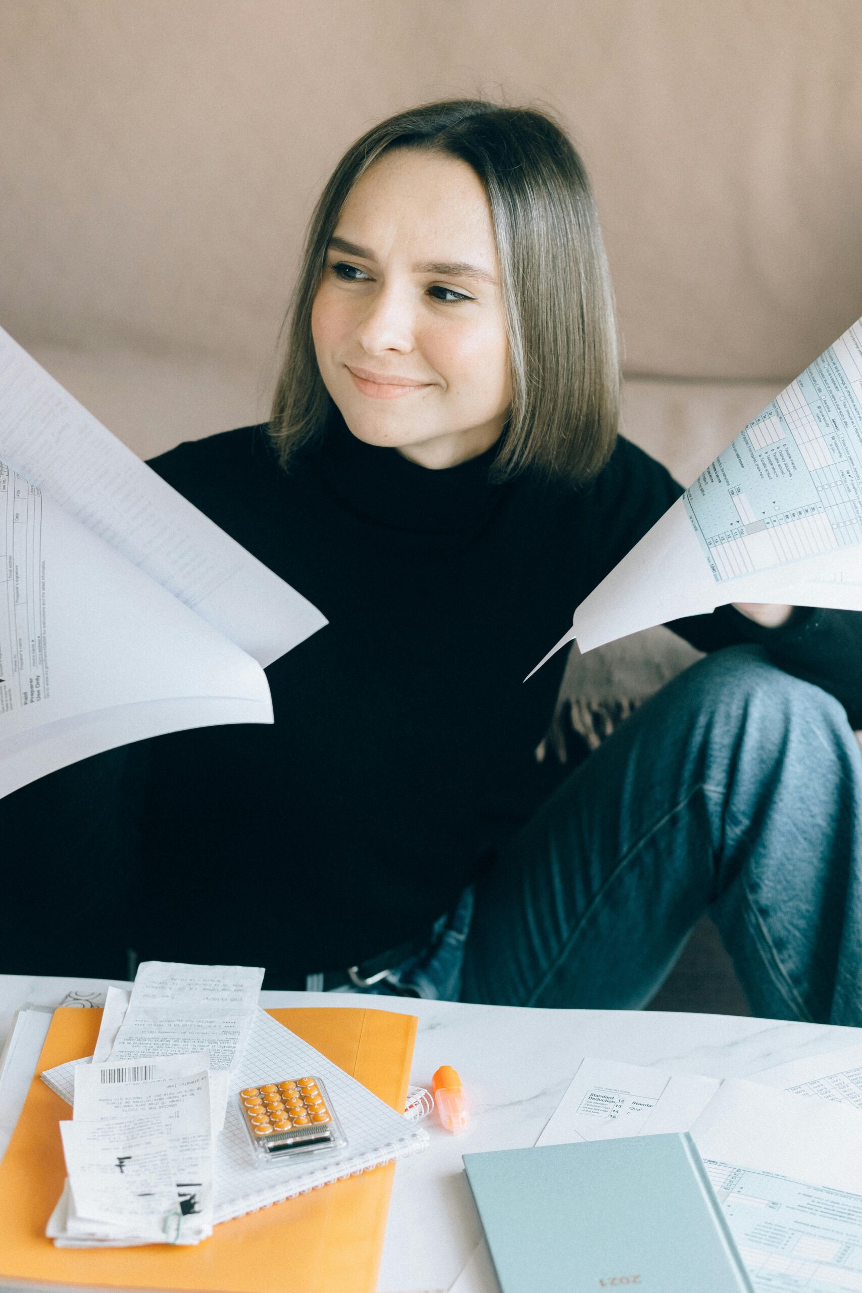 Young woman sorting tax documents and papers at home office desk.